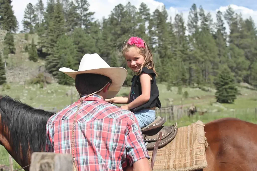 Young girl on horse getting lessons from a wrangler